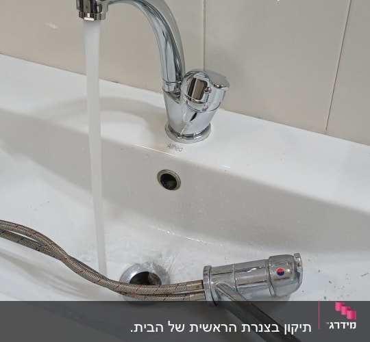 ברז מים זורם בכיור עם צינור גמיש